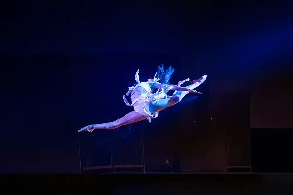 Performer in a dynamic floor pose during an SDT scene.